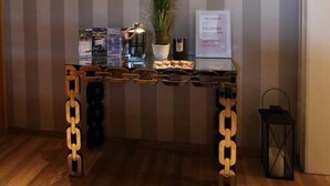 Un comptoir d’accueil agrémenté d’une plante en pot, d’un panneau indicateur et d’une petite table sur laquelle sont posés divers objets.