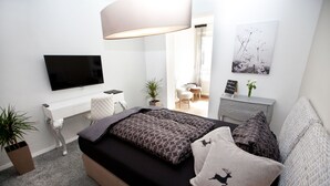 Une chambre moderne comprenant un lit, un bureau, une télévision et un petit coin salon.