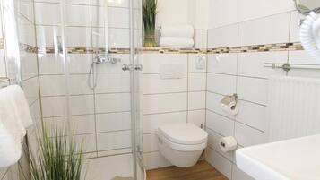 Ein modernes Badezimmer mit Duschkabine aus Glas, Toilette und Badewanne.