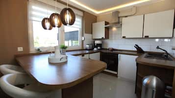 A modern kitchen with a central island, white cabinets, and pendant lighting.
