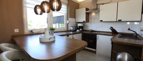 A modern kitchen with a central island, white cabinets, and pendant lighting.