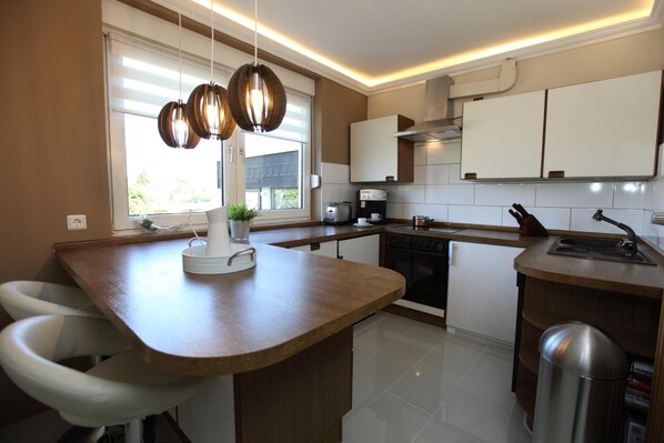 A modern kitchen with a central island, white cabinets, and pendant lighting.