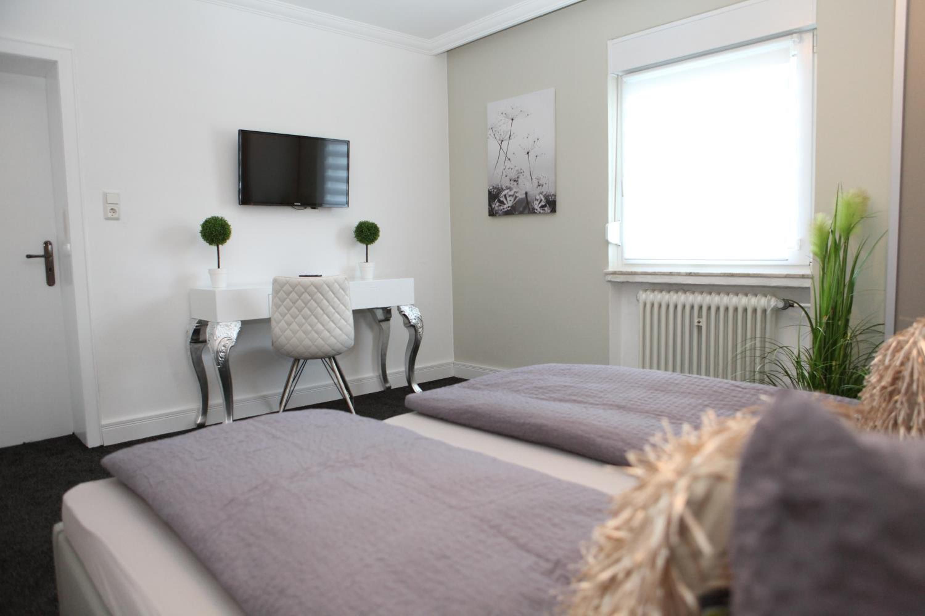 Una camera d'albergo con un letto, una televisione, una finestra e un termosifone.