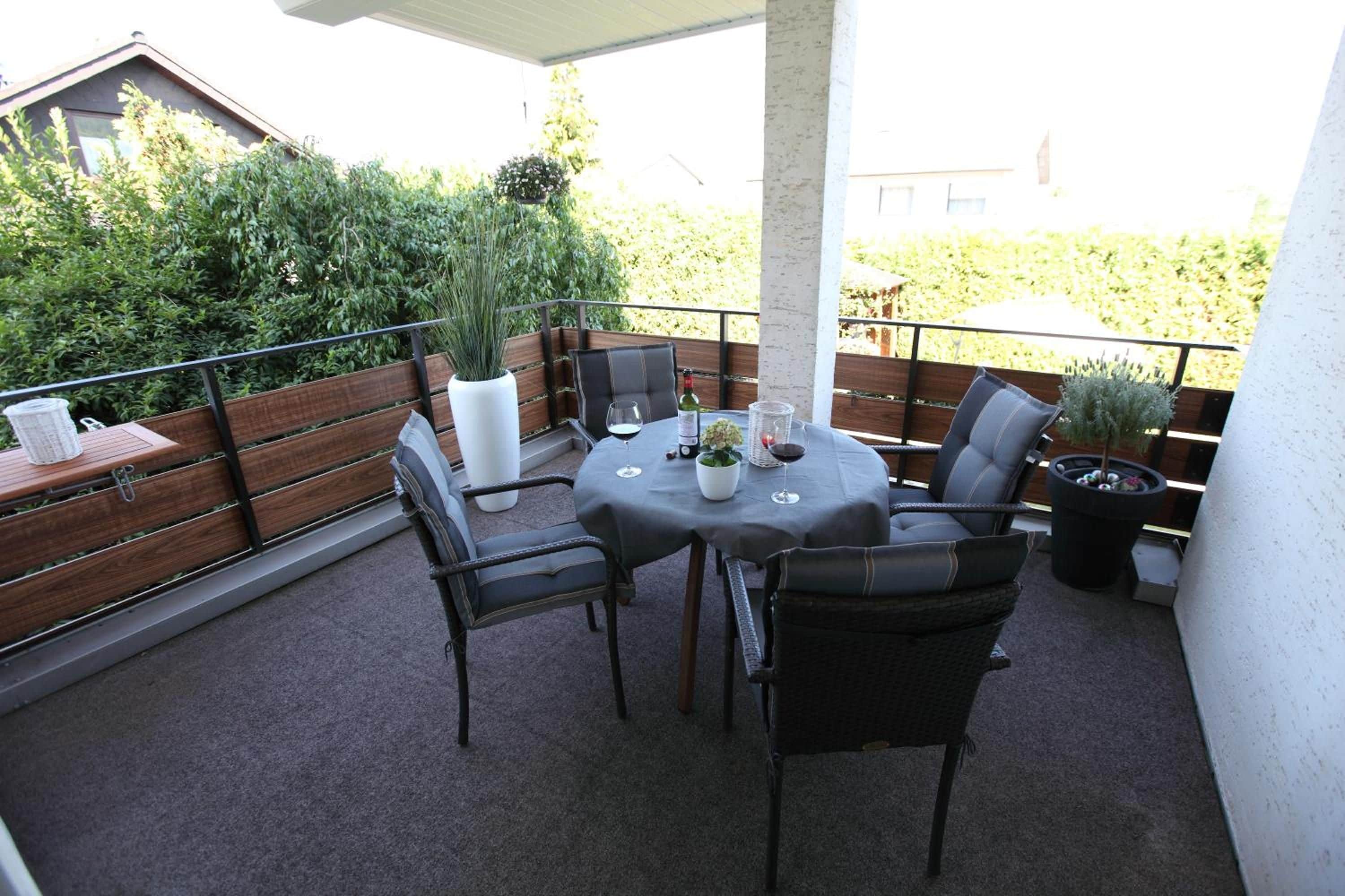 Eine Terrasse im Freien mit einem runden Tisch, vier Stühlen und einem Blumentopf.