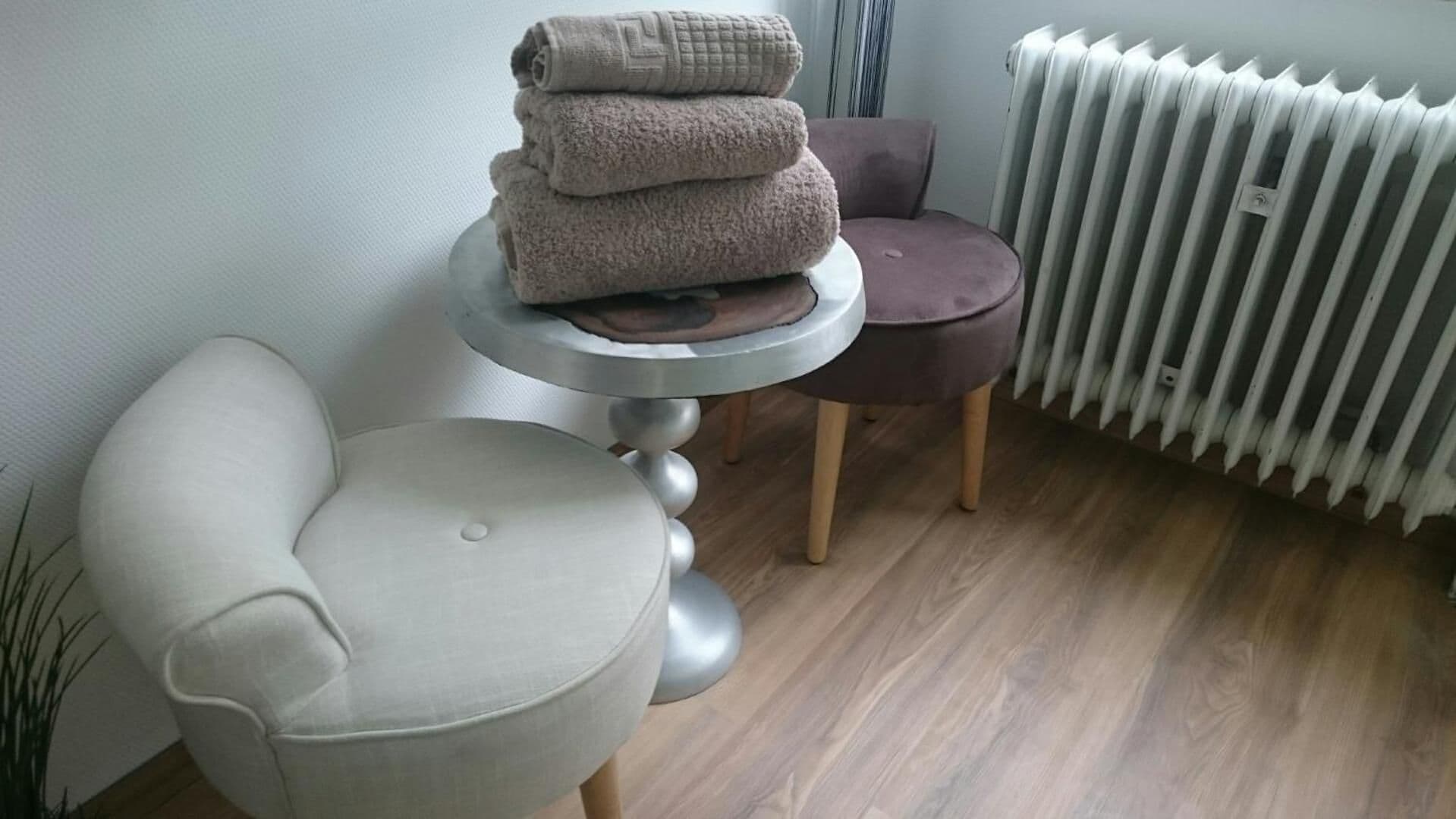 Ein Zimmer mit einem runden Tisch, einem Stuhl, einem Heizkörper und einer Pflanze.