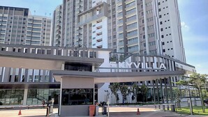 Un immeuble moderne de grande hauteur, doté d’une entrée imposante portant l’inscription « SKYVILLA ».