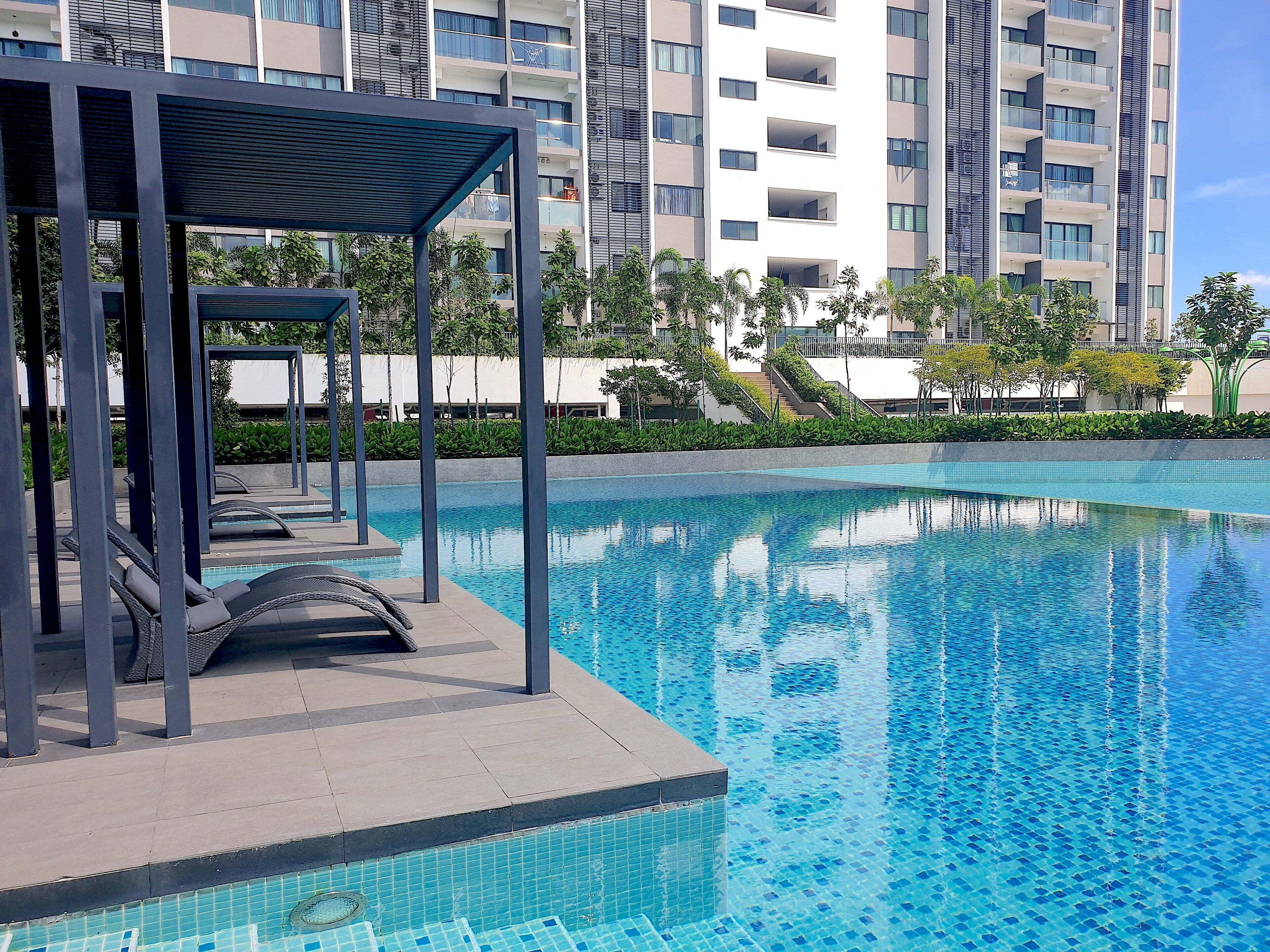 Piscina moderna com água azul cristalina, rodeada por uma área coberta com espreguiçadeiras.