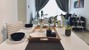 Un salon moderne avec un coin repas, doté d’un ventilateur de plafond, d’un appareil de climatisation et offrant une vue à travers de grandes fenêtres équipées de rideaux.