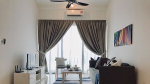 Un salon moderne doté d’un téléviseur à écran plat, d’un canapé, d’une table basse et d’un ventilateur de plafond.