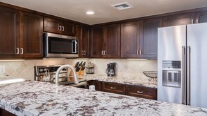 A kitchen with dark wood cabinets, stainless steel appliances, and a marble countertop. - Snowcreek #856 Phase V (Mammoth Lakes)