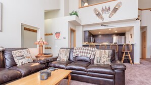 A spacious living room with a leather sofa, a wooden coffee table, and a kitchen area in the background. - Snowcreek #856 Phase V (Mammoth Lakes)