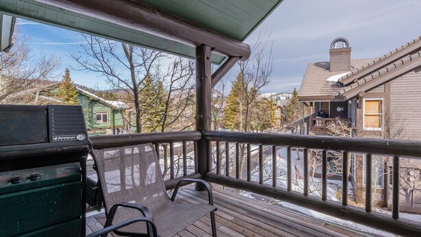 A wooden deck with a grill, chairs, and a view of houses and trees. - Snowcreek #856 Phase V (Mammoth Lakes)