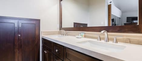 A bathroom with a double sink vanity, dark wood cabinets, and a large mirror.