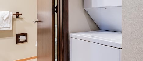 Un lavadero con lavadora y secadora, una puerta de madera y un perchero.