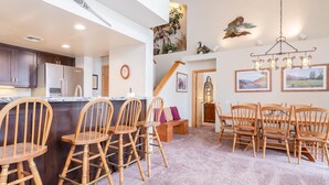 A spacious kitchen with modern appliances, a dining area with wooden chairs, and a staircase leading to an upper level. - Snowcreek #856 Phase V (Mammoth Lakes)