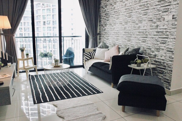 Ein modernes Wohnzimmer mit Steinwand, einer Couch, einem Couchtisch und Blick auf ein Hochhaus.