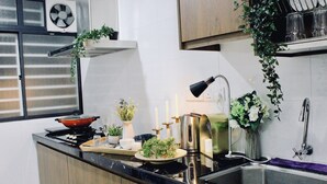 Eine moderne Küche mit Gasherd, Spüle und Edelstahlgeräten. Auf der Arbeitsplatte befinden sich Pflanzen, Kerzen und eine Kaffeemaschine.