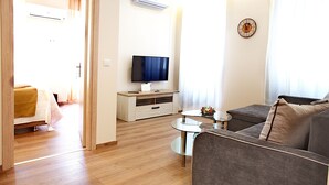 A modern living room with a sofa, a TV, and a small table. - Liston Suite Plaza (Corfu)