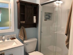 A bathroom with a glass shower enclosure, a white toilet, and a wooden medicine cabinet above the sink. - SHORT WALK TO VILLAGE, BEACH - HEATED POOL - LUSH LANDSCAPING
2 SEPARATE UNITS. (Siesta Key)