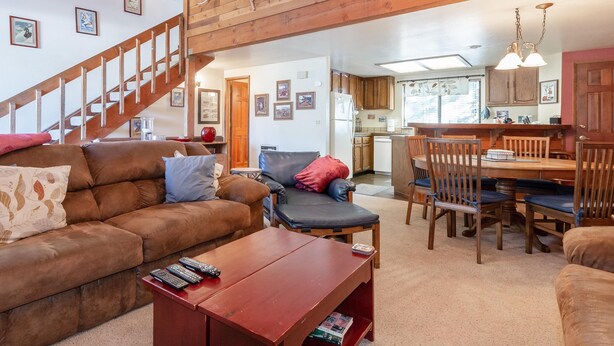 A cozy living room with a brown sofa, a wooden coffee table, and a staircase leading to another level.