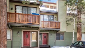 A two-story building with a green facade, numbered doors, and a wooden balcony.