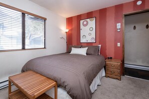 A bedroom with a bed, bedside table, and a wall-mounted artwork.