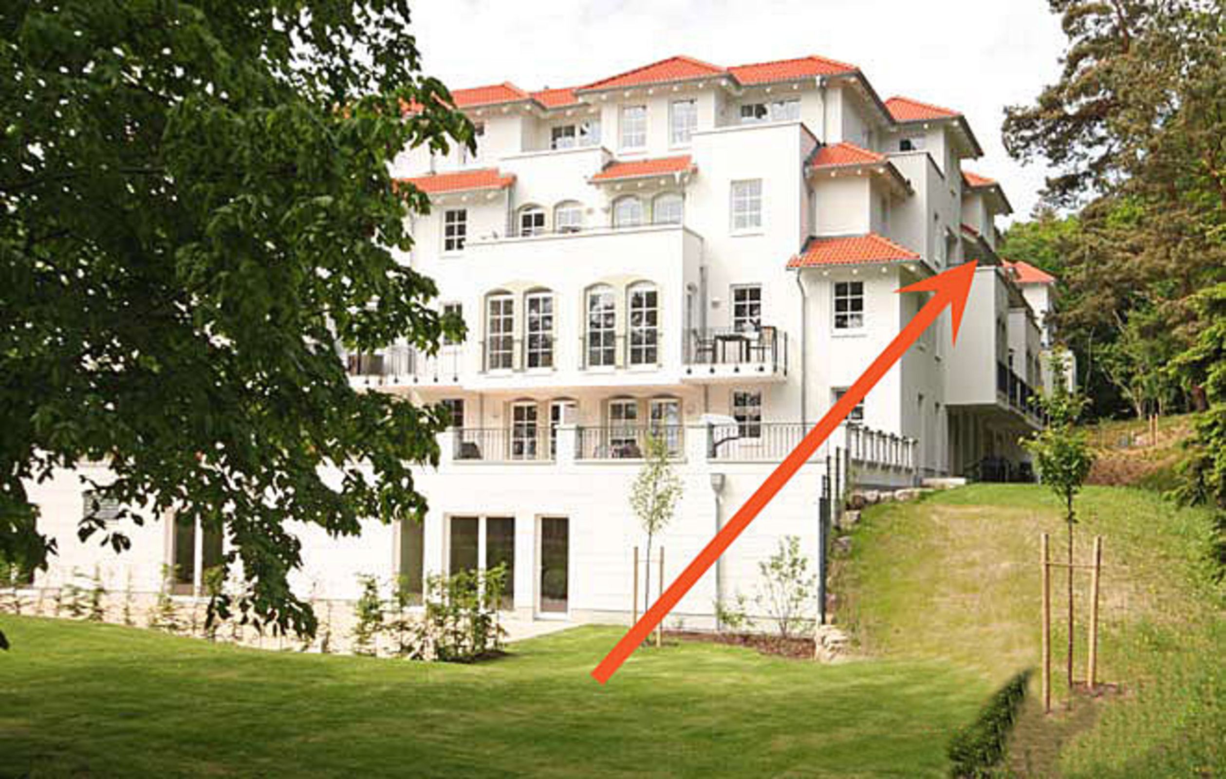 Ein mehrgeschossiges Hotel mit rotem Ziegeldach, großen Fenstern und einem gepflegten Rasen.