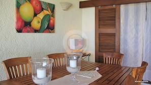 A wooden table with two glass candle holders, a white candle, and a decorative plate.