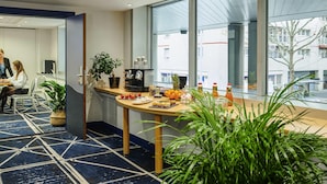Une salle de conférence moderne dotée d’une grande fenêtre, d’une machine à café et d’une table où sont disposés des en-cas.