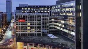 Un bâtiment moderne avec une façade en verre, une enseigne « Mercure » bien visible et un espace extérieur couvert avec des marches menant à l’entrée.
