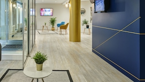 Un hall d’entrée moderne avec un plancher en bois, un mur d’accent bleu, une grande colonne et un téléviseur fixé au mur.