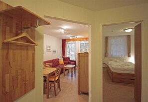 A room with a bed, a dining table with chairs, a sofa, and a wooden wardrobe. - Haus Meeresblick FeWo Abendrot A 1.31 Ref. 132364 - FeWo Abendrot A 1.31 Ref. (Baabe)