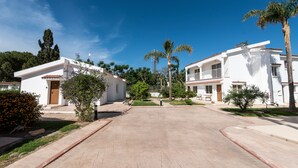 A residential area with white buildings, palm trees, and a clear blue sky. - Fig Tree Z Holiday Villas DPS09- Three Bed Bungalow (Protaras)