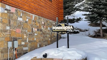 Un mur de pierres, une cabane en bois et une pancarte indiquant « Ponderosa Valley ».