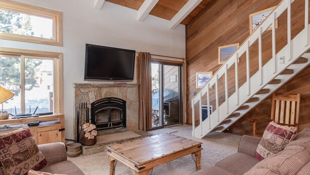 Una sala de estar acogedora con chimenea, televisor de pantalla plana y una escalera.