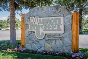 A sign for Mammoth Creek Condominiums with a stone base and wooden pillars. - Mammoth Creek #52 (Mammoth Lakes)