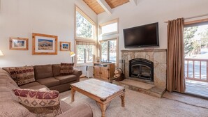 Una sala de estar acogedora con chimenea, televisor y un ventanal grande.