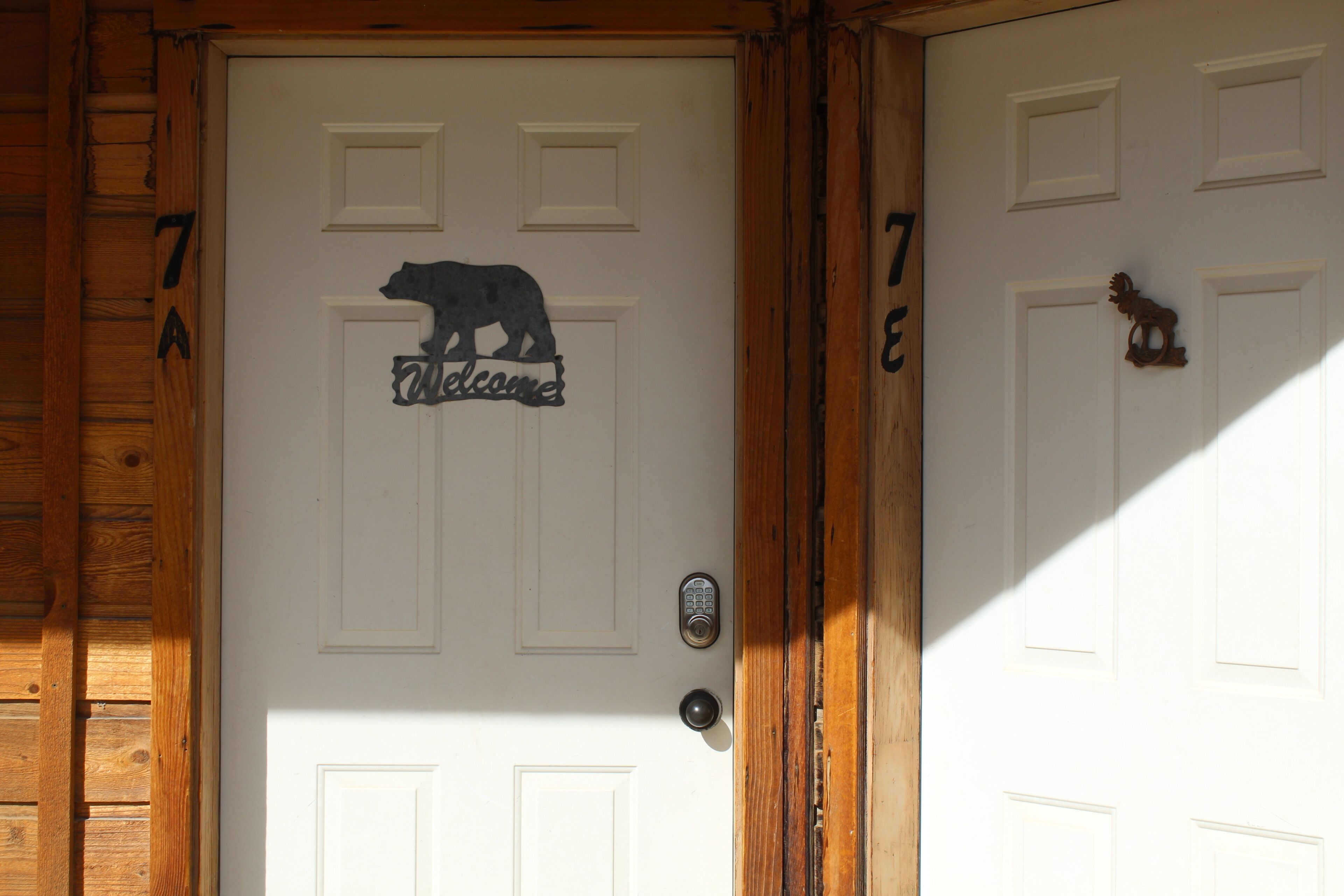 A wooden door with a bear-shaped welcome sign and a keypad lock.