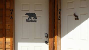 A wooden door with a bear-shaped welcome sign and a keypad lock.