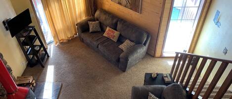 A cozy living room with a gray sofa, a ceiling fan, and a fireplace.