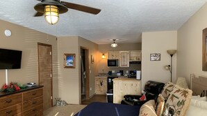 Ein Schlafzimmer mit Bett, Kommode, Fernseher und Deckenventilator.