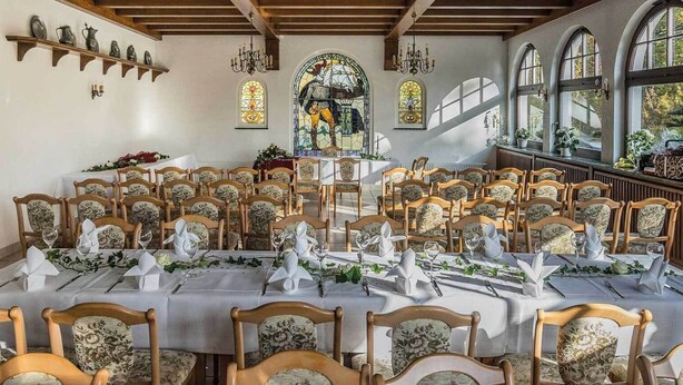 A dining area with multiple tables set for a meal, surrounded by wooden chairs with floral upholstery.
