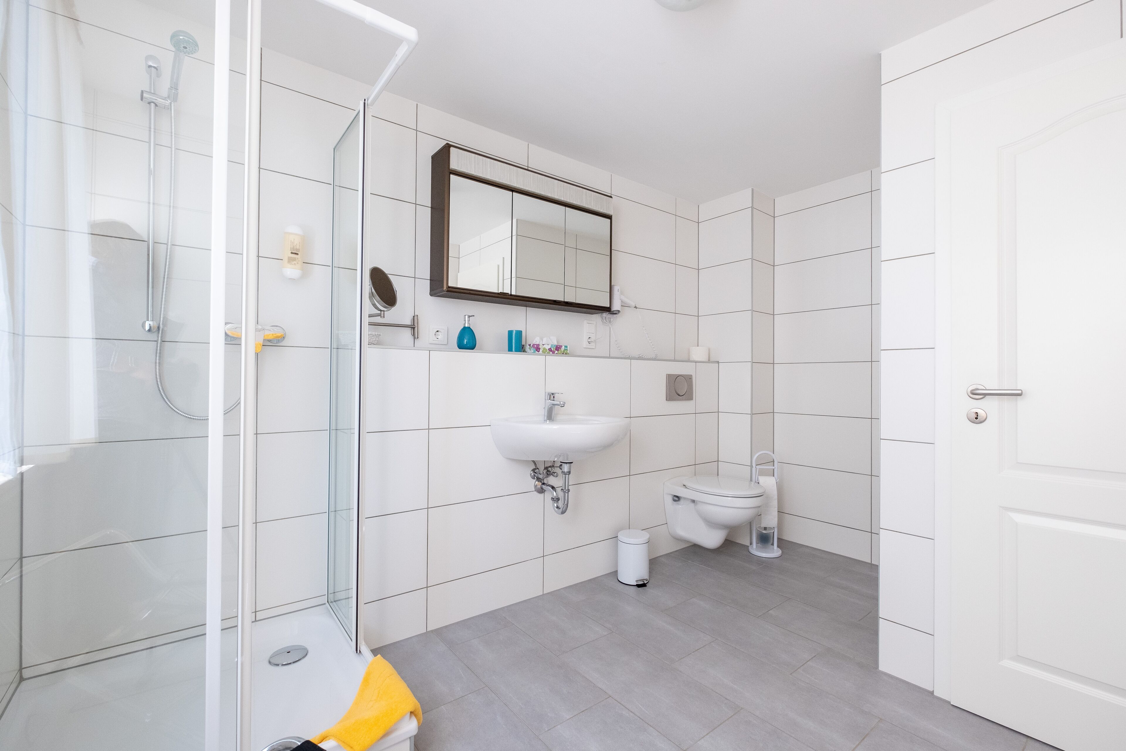A modern bathroom with a glass shower enclosure, a white sink, and a toilet.