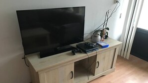 A wooden TV stand with a flat-screen TV, gaming console, and remote control.