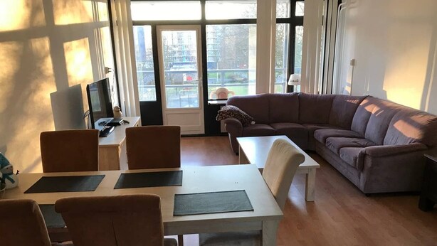A living room with a dining area, a sofa, and a TV.