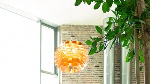 A modern interior with a large window, a brick wall, and a hanging orange light fixture. - Flowers Hotel Essen (Essen)