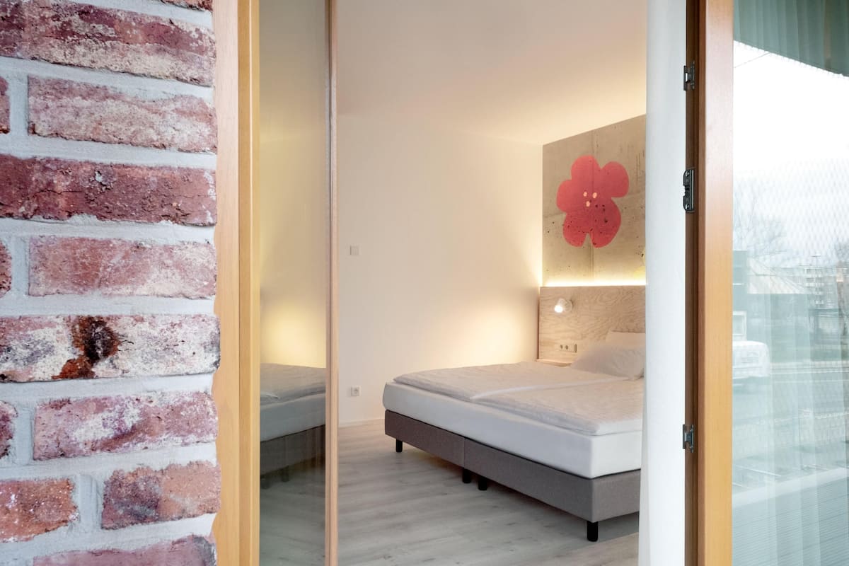 Ein Schlafzimmer mit Backsteinwand, einem Bett, einem großen Spiegel und einer Wandleuchte.