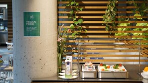 Uma estação de comida vegana com um letreiro, um dispensador de sucos e um bar de saladas.