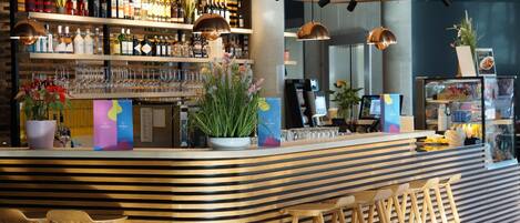 A bar area with shelves of bottles, a potted plant, and a counter with stools.