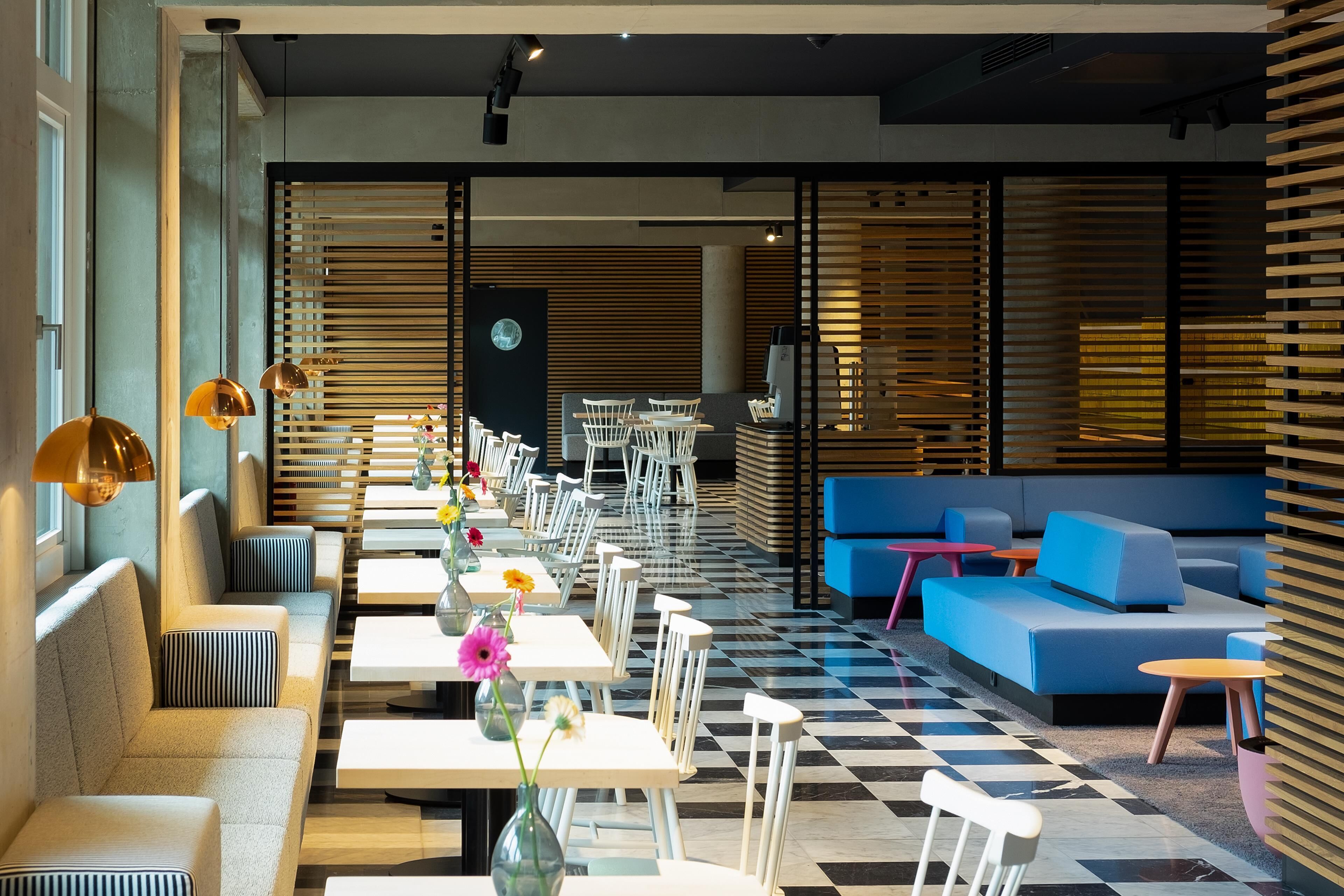 Ein modernes Interieur mit Sitzbereichen, Tischen und einer Rezeption.